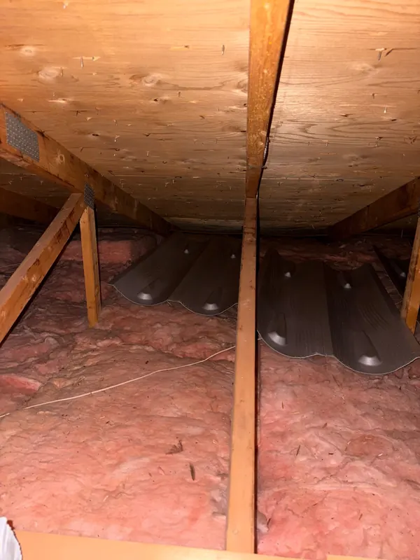 Grenier avant les travaux : nattes de laine rose entre les solives, déflecteurs de ventilation sous le toit